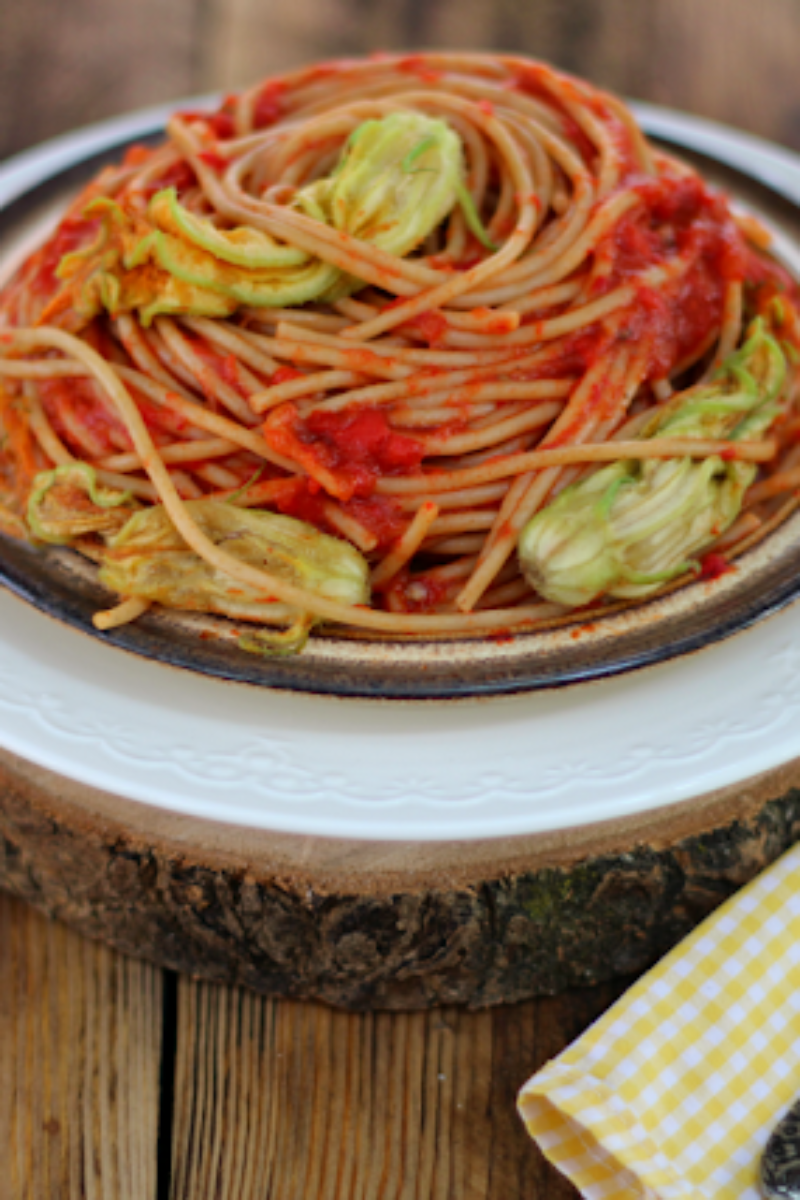 Pełnoziarniste spaghetti z pastą ajvar i kwiatami cukinii.